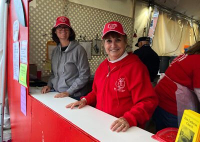 Two women in red jackets standing behind a counter, ready to assist customers with their needs.
