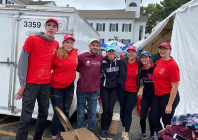 A group of people in red shirts standing next to a white trailer.